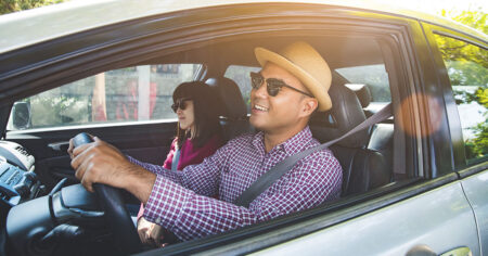 A man and a woman enjoying a drive in the car on a sunny day