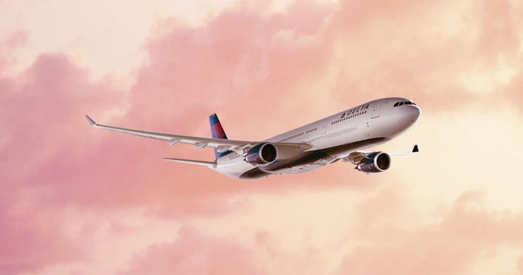 An airplane flying against a pink sky backdrop