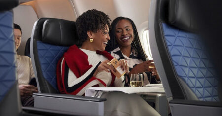 Two women enjoying a conversation and drinks on an airplane