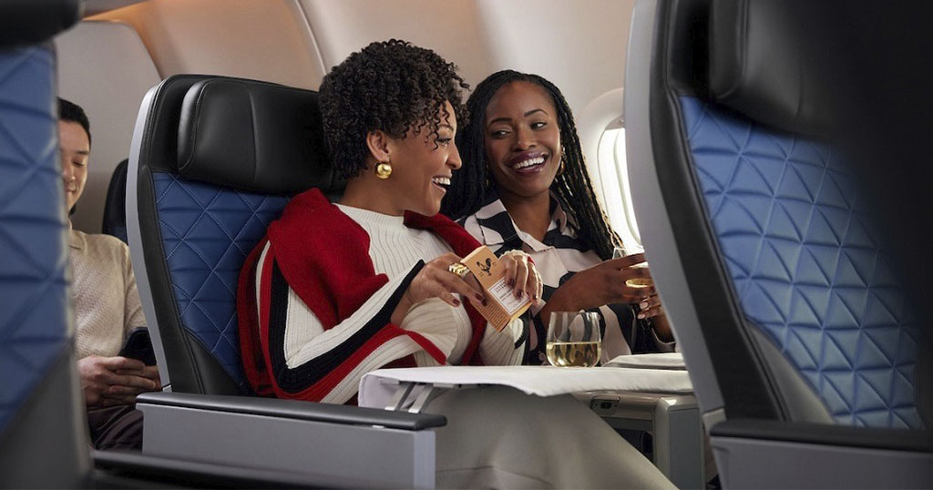 Two women enjoying a conversation and drinks on an airplane