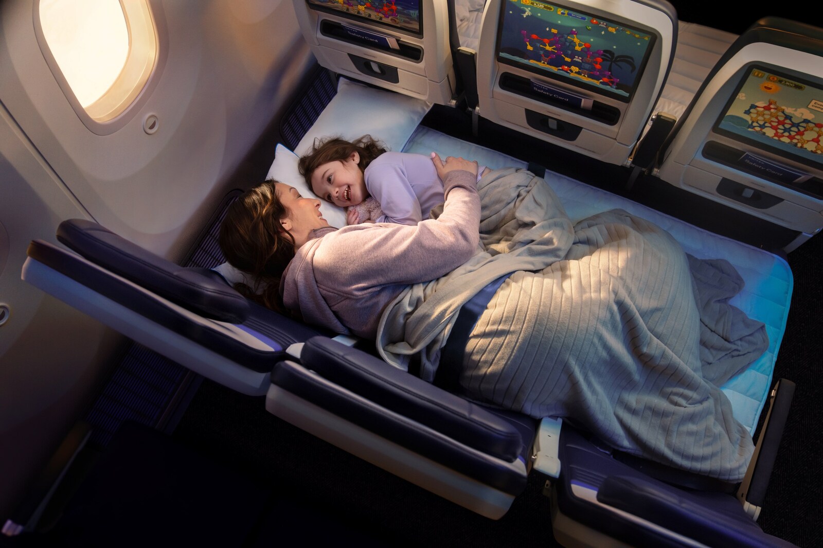 Parent and child lying on the United Relax Row economy couch seats