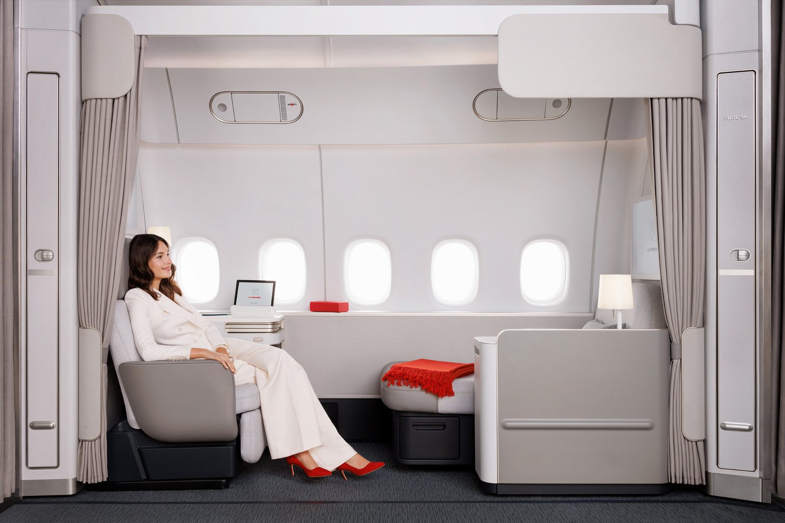Passenger seated in the new Air France La Première suite next to five cabin windows