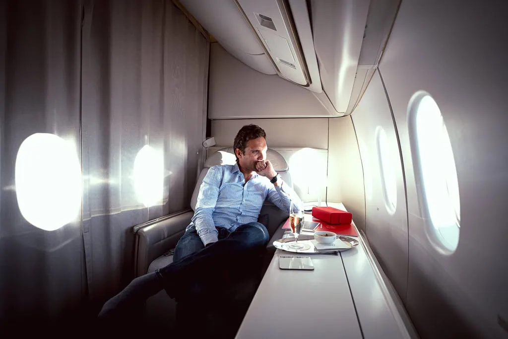 Jean-Maximilien Voisine seated in the previous Air France La Première cabin with a glass of champagne on the tray table