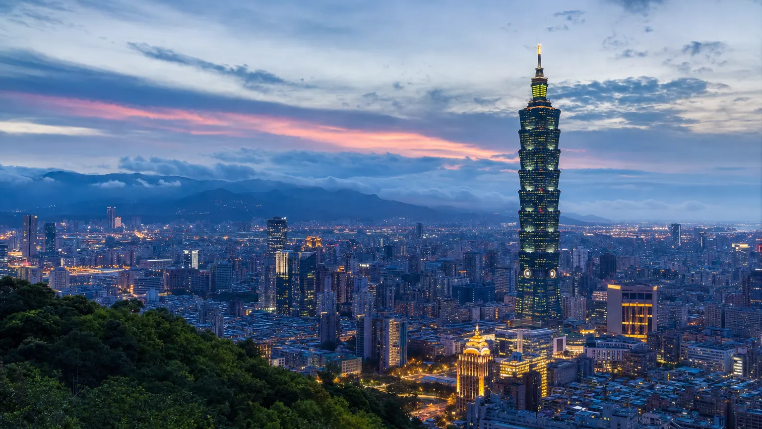 Taipei skyline at blue hour seen from a green hillside, with a tall tiered skyscraper above the city